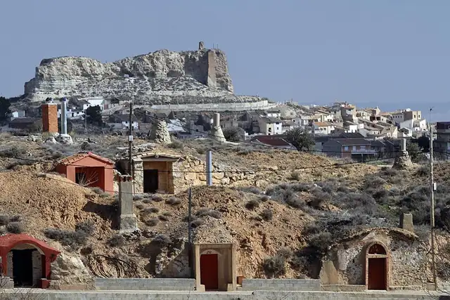 Bodegas excavadas en el cerro, con el pueblo y la peña del castillo detrás